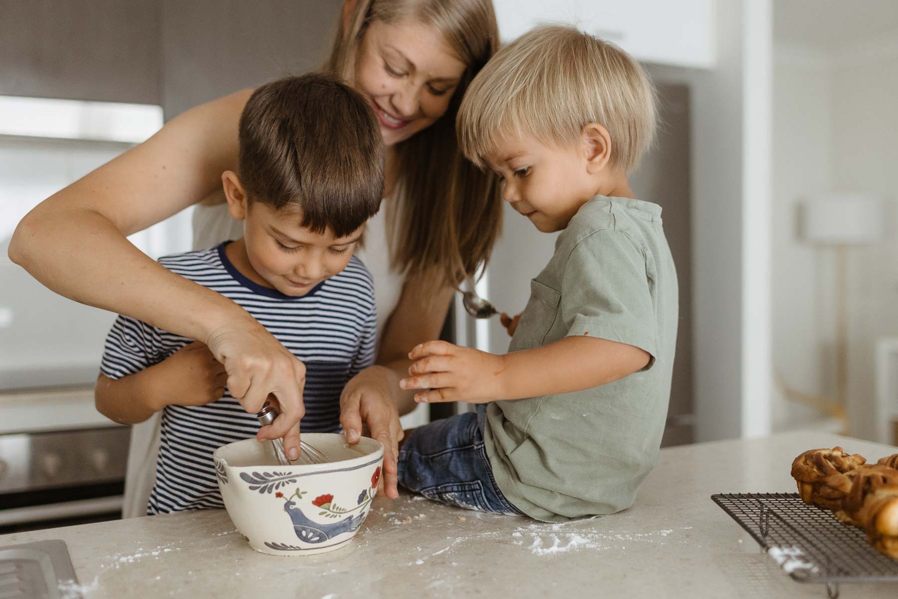 Young mother and young sons mixing at kitchen bench